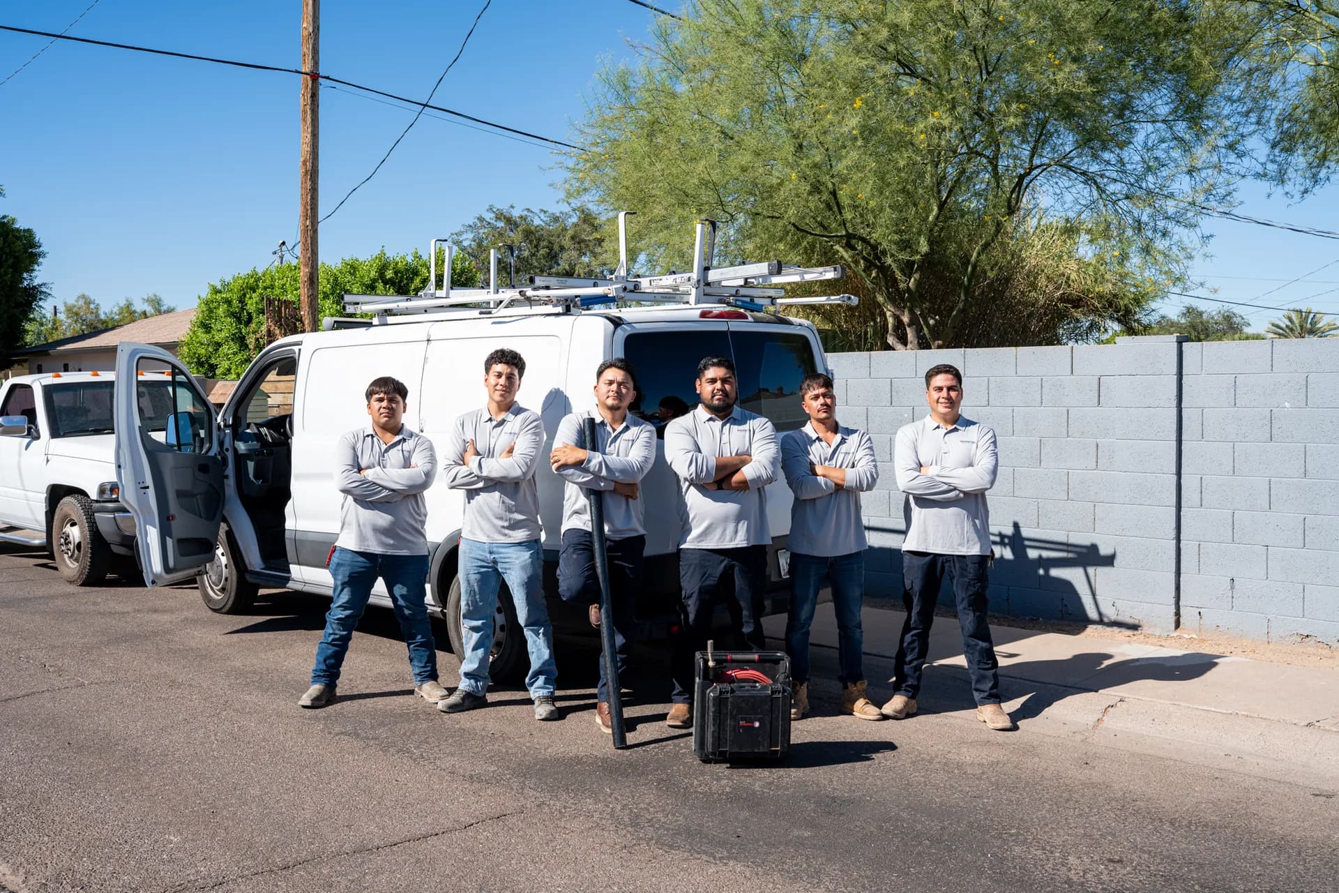 The Warriors Plumbing & Rooter crew standing together in front of their service vans