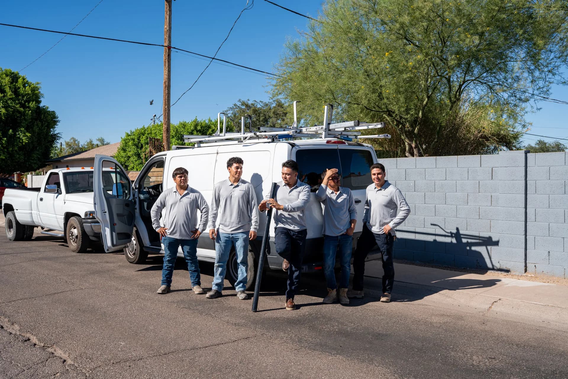 Warriors Plumbing & Rooter crew standing with their work van and truck on a Phoenix street