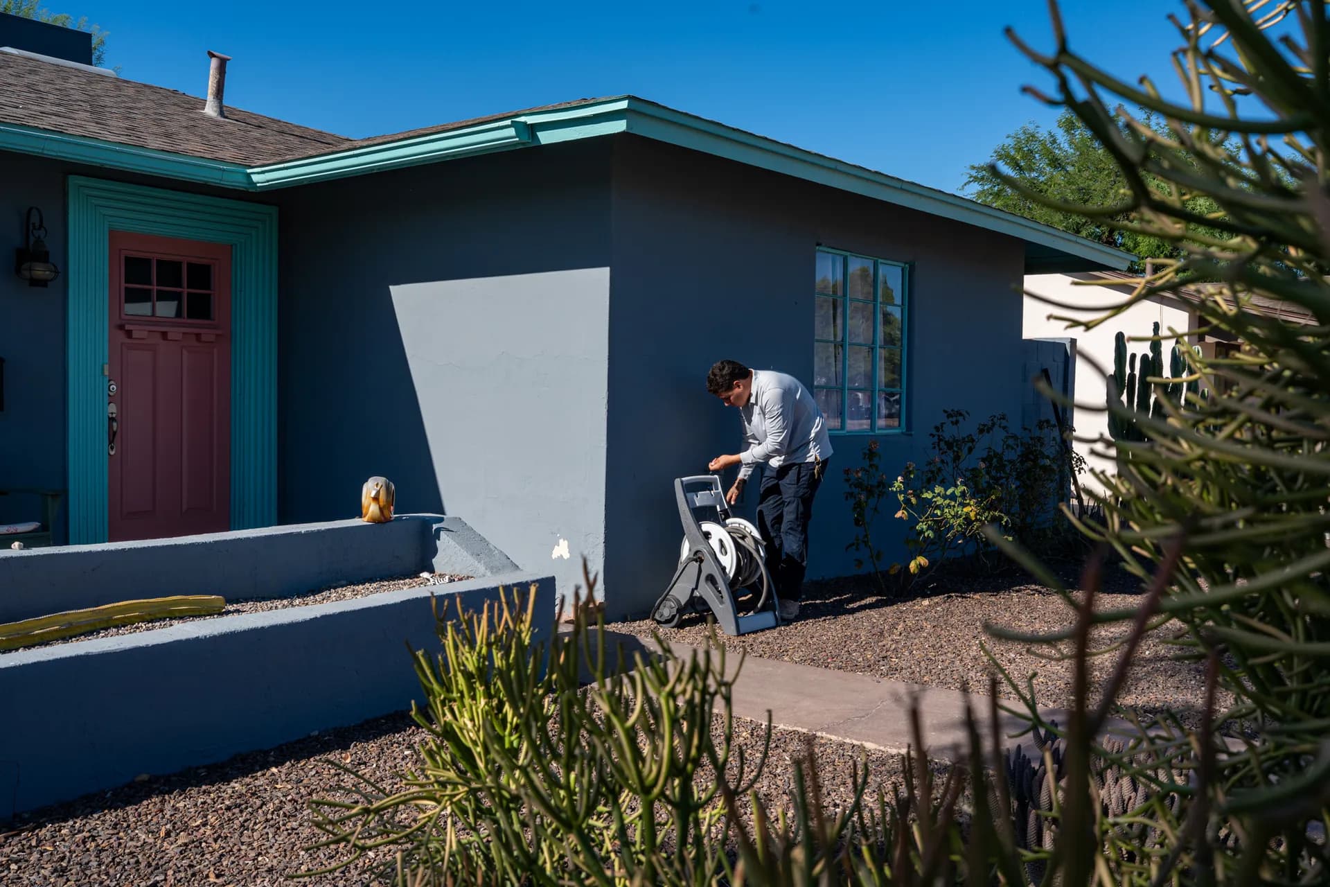 Warriors Plumbing & Rooter technician setting up a hose reel outside a Phoenix home